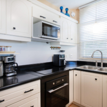 Kitchen of the Portofino two‑bedroom apartment, fully equipped with refrigerator/freezer, dishwasher, oven, cooktop, microwave, air‑fryer, electric kettle and Nespresso coffee machine.