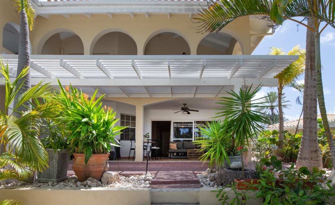 View of the Portofino two‑bedroom ground‑floor apartment from the private tropical garden