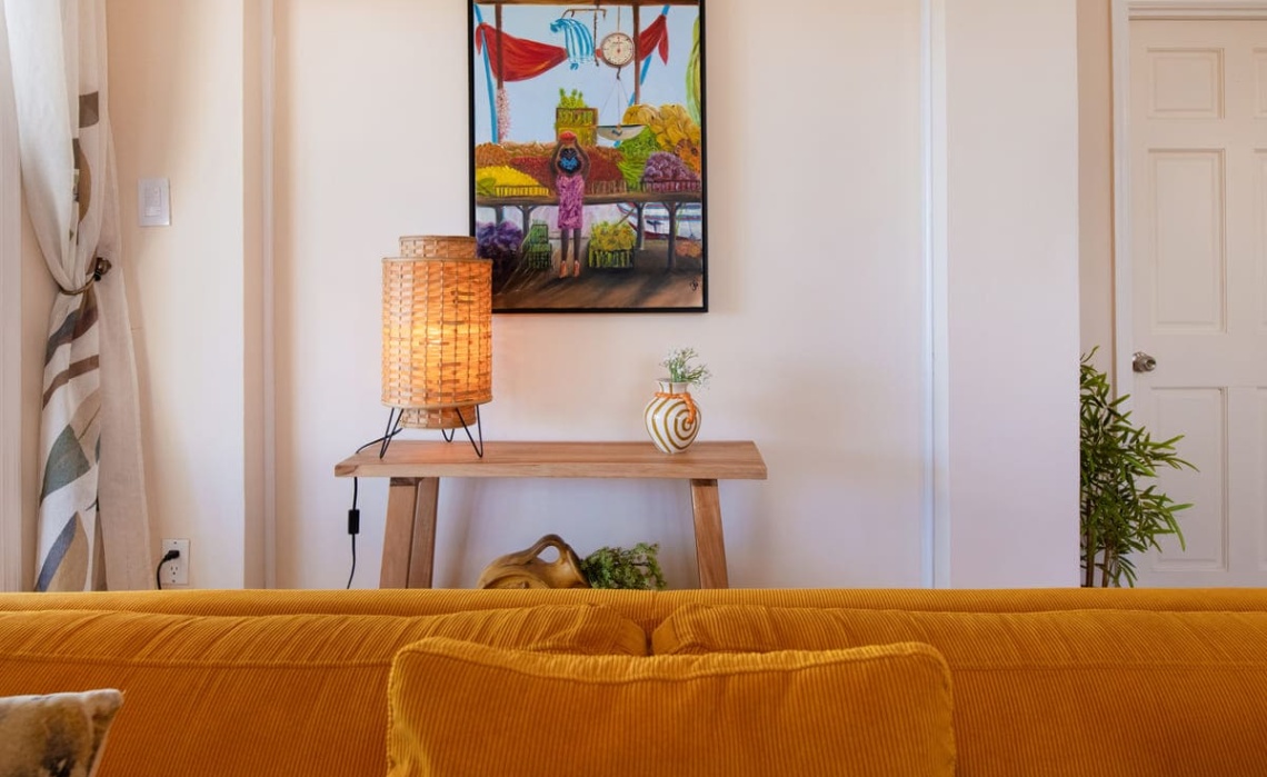 Living room of the Portofino two‑bedroom apartment, furnished with a sofa and decorated with wall paintings that add a splash of colour to the space.