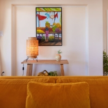 Living room of the Portofino two‑bedroom apartment, furnished with a sofa and decorated with wall paintings that add a splash of colour to the space.