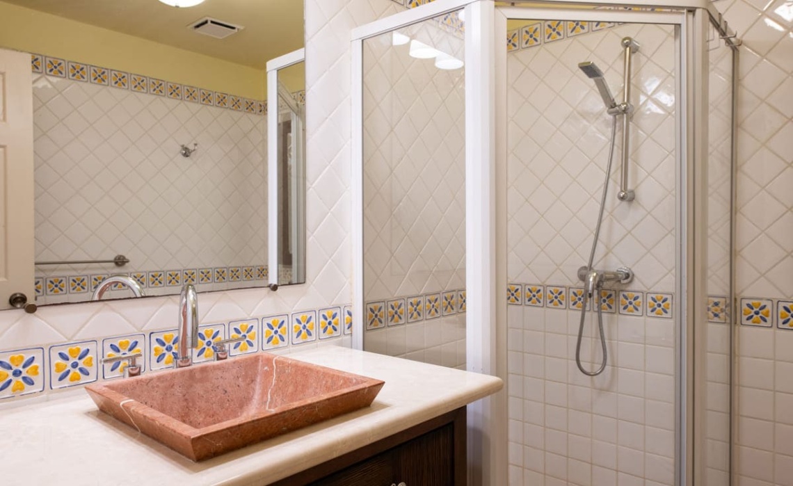 Bathroom with shower in the Portofino two‑bedroom apartment, featuring a glass‑enclosed shower, modern fixtures, vanity and ceiling fan.