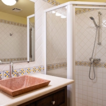 Bathroom with shower in the Portofino two‑bedroom apartment, featuring a glass‑enclosed shower, modern fixtures, vanity and ceiling fan.