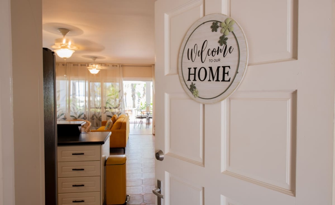 Front door of the Portofino two-bedroom apartment open, revealing the entrance hallway and bright interior.