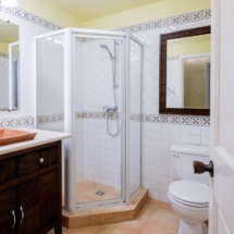 Bathroom shower area in Portofino: glass enclosure, tiled floor, vanity and ceiling fan for a relaxing stay.